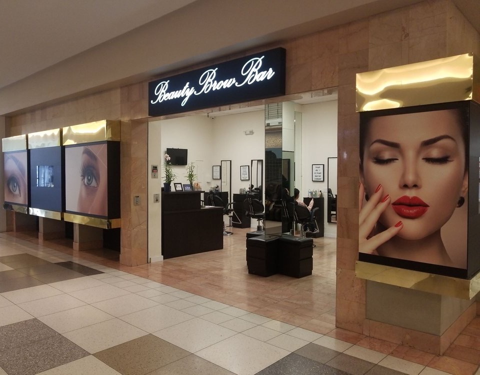 The Beauty Brow Bar storefront inside Eagle Rock Plaza, with a lit script sign over black and gold framing